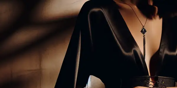 A vulnerable yet empowered female figure in a dimly lit room, symbolizing eroticism and power dynamics.